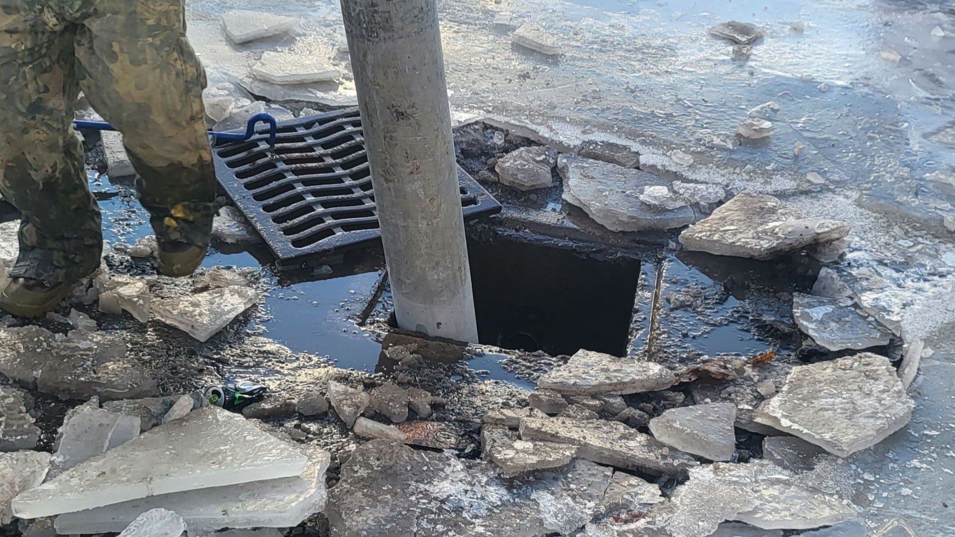 AQUALIS employee opening up a sewer grate around ice during a freeze-thaw cycle